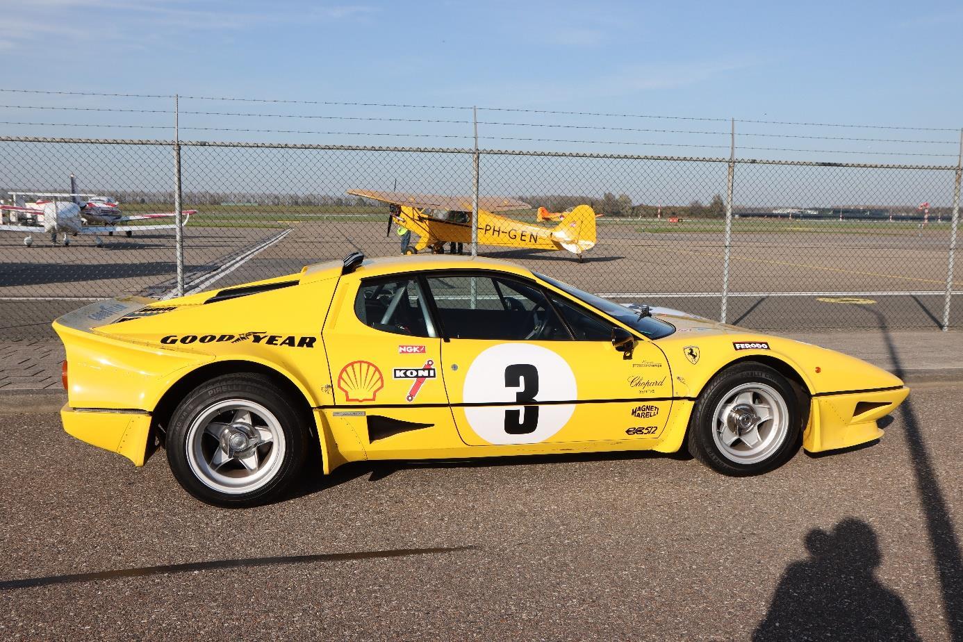 Side profile of a modified yellow Ferrari 512 BB with number 3, silver wheels and a raised integral rear spoiler.